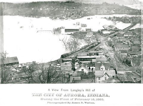 Black and white photograph showing a flooded town; caption reads: 'A View From Langley's Hill of The City of Aurora, Indiana, during the Flood of February 16, 1883. Photographed by James N. Walton.'